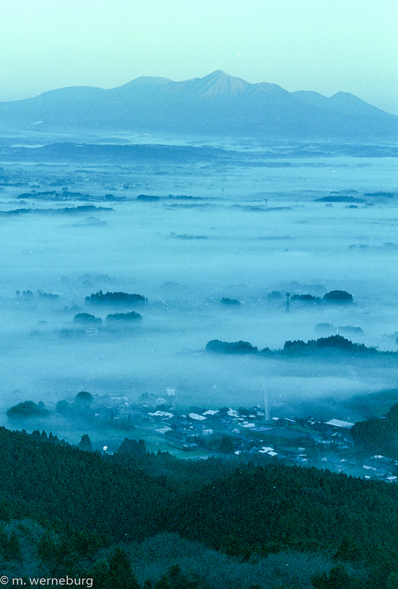 mountain and moon overlooking a cloud-filled lowland